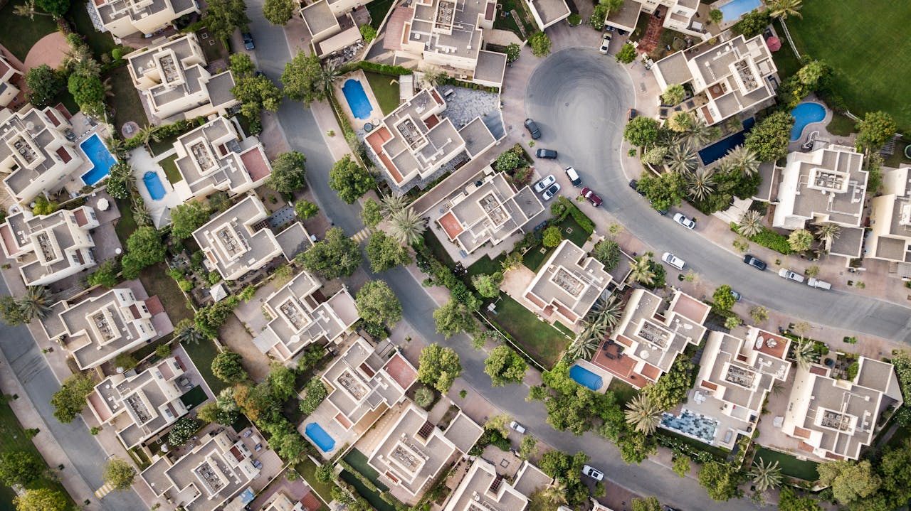 services-02 Explore a stunning aerial view of a residential area in Dubai with lush greenery and swimming pools.