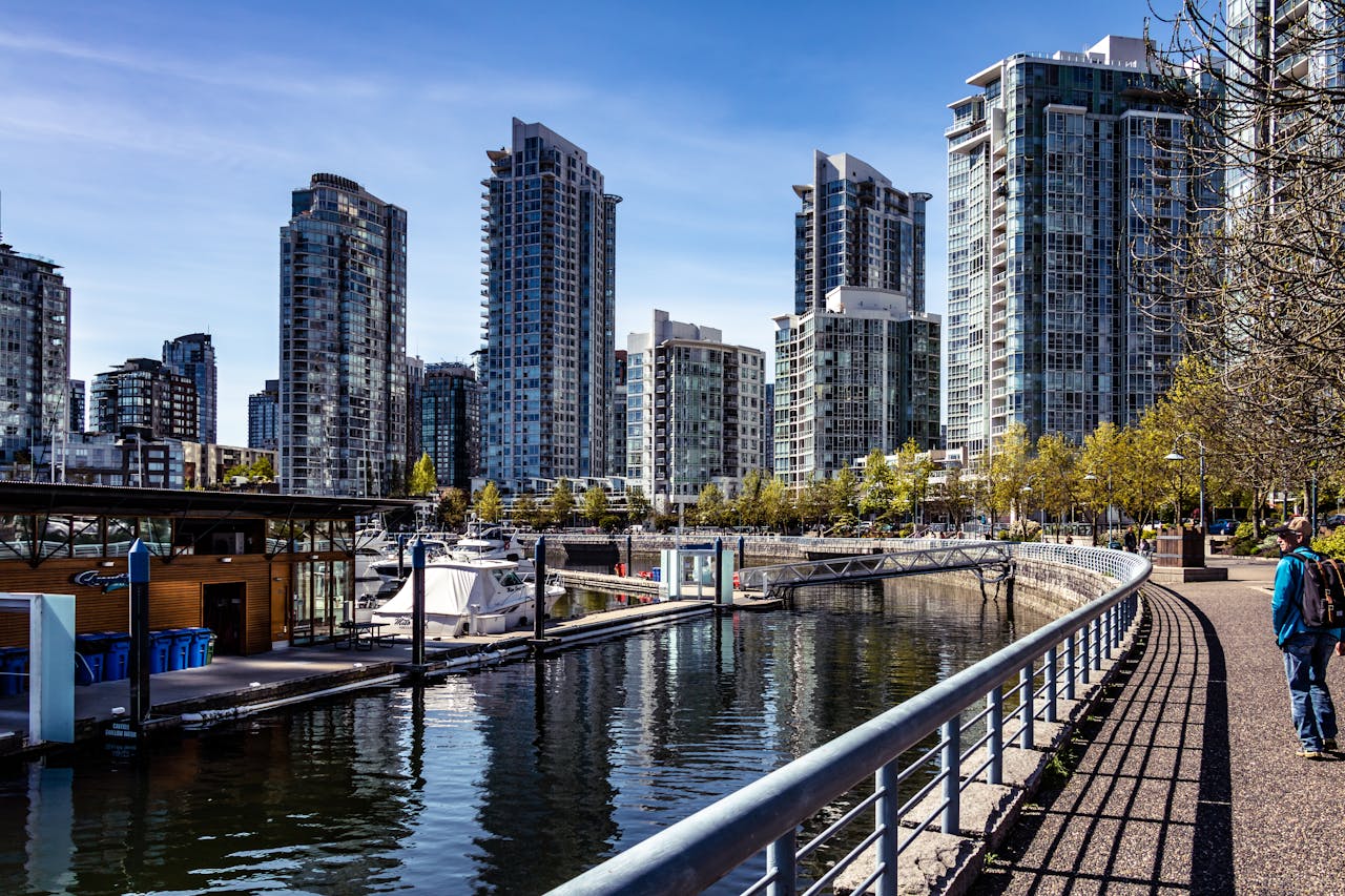 about-us Modern skyscrapers reflect on the serene Vancouver waterfront in a bustling urban scene.
